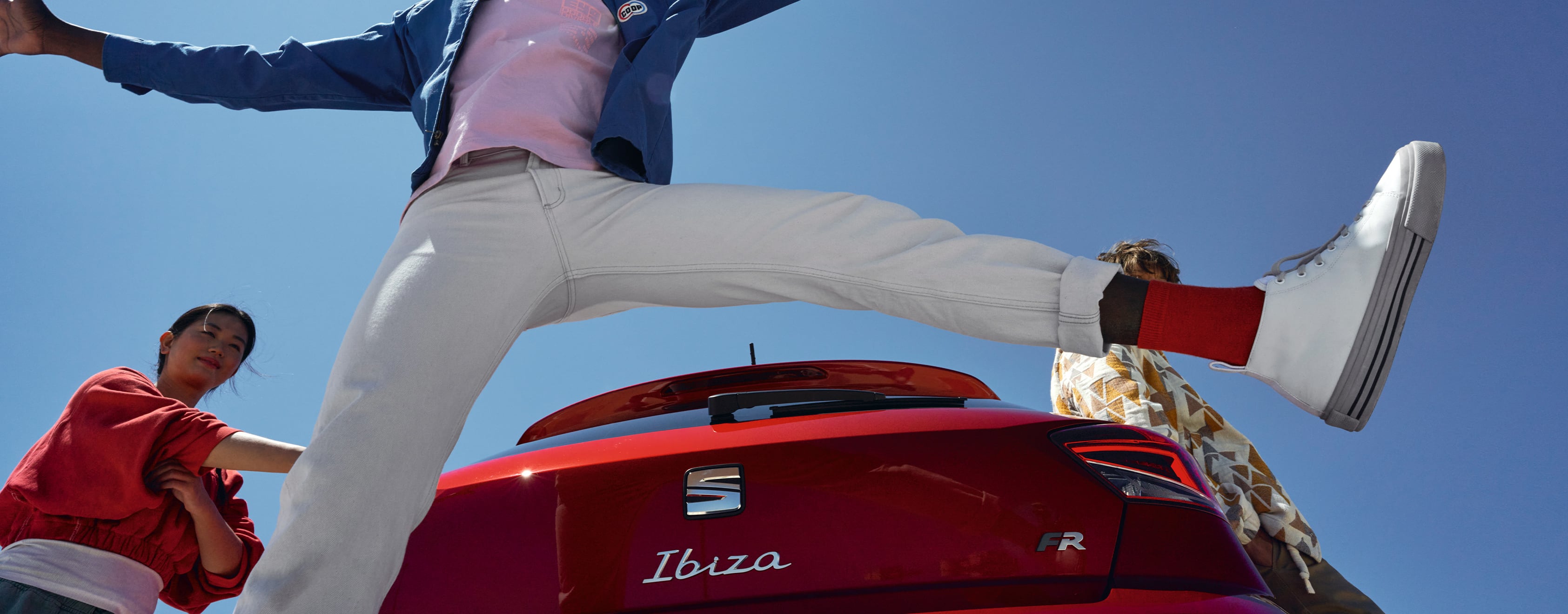 Mies hyppää ilmaan Desire Red -värisen Seat Ibizan takana